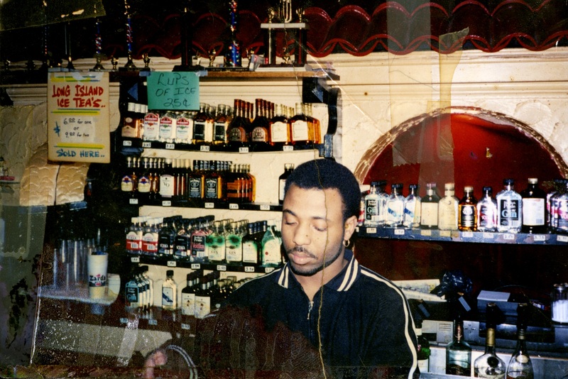 Danny Cashmere bartends at Soakie's, with a wall of liquor and trophies behind him.