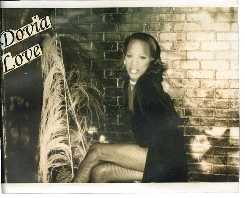 Dovia Love sits cross-legged in front of a brick wall at Soakie's. 